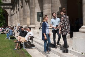 Three students talk while in the courtyard at the main building of the University of Vienna