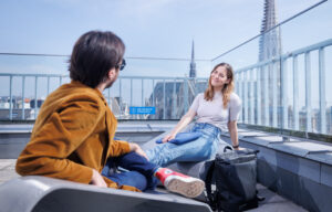 2 Studierende sitzen auf der Dachterrasse des NIG und reden miteinander