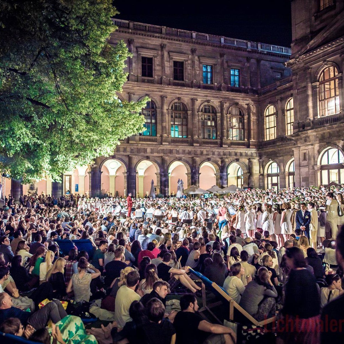 Mit vielen Menschen gefüllter Arkadenhof der Universität Wien, abends, bei Sommernachtkonzert der Philharmonie