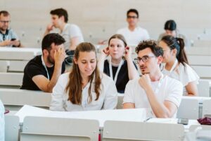 A group of people, sitting in rows of work places, in conversation with each other at a brainstorming session on ilabs.