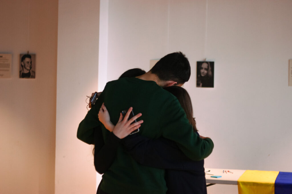A group of people hugging emotionally, at the exhibition opening.