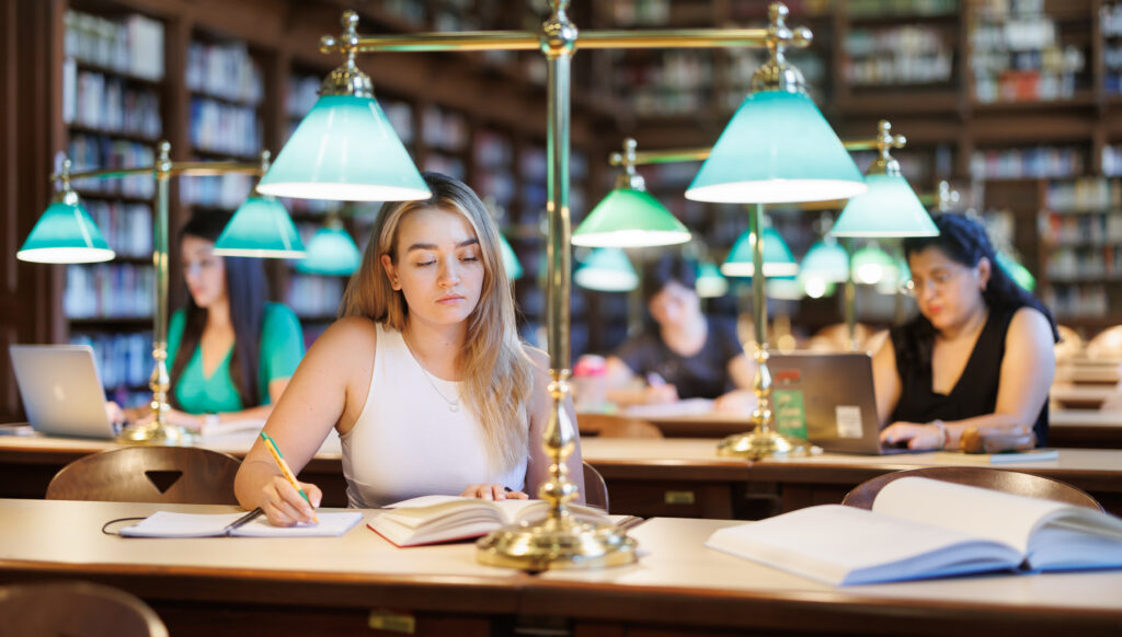 Eine Studierende sitzt in einer Fachbibliothek und liest