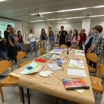 A group of researchers stands around a table which is filled with art materials