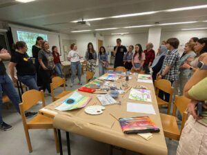 A group of researchers stands around a table which is filled with art materials