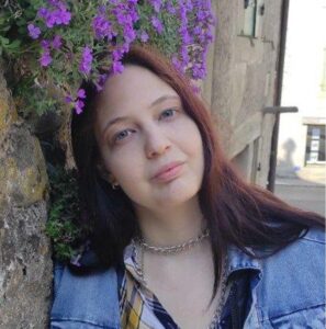 Female student with red hair and a jeans jacket.