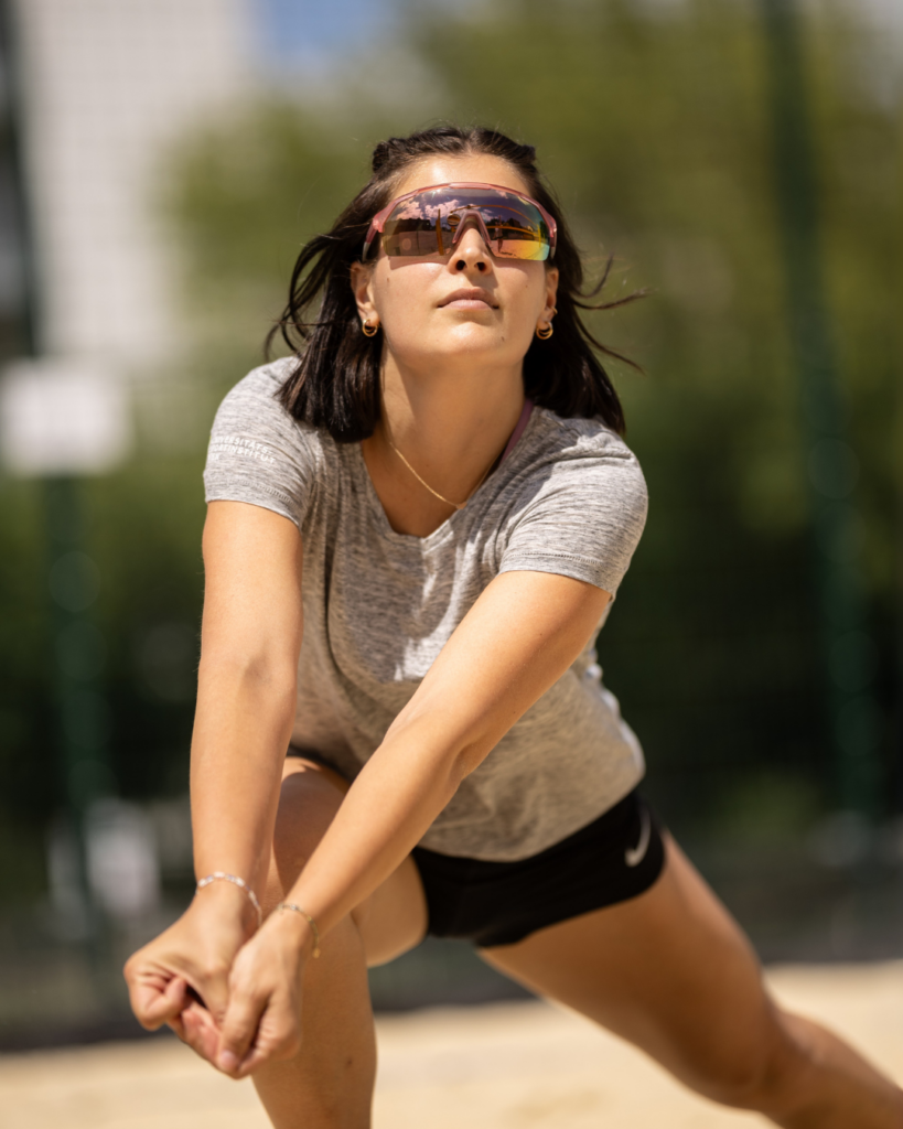 Frau mit Sonnenbrille beim Volleyballspielen. Sie bereitet sich auf ein unters Zuspiel (baggern) vor.